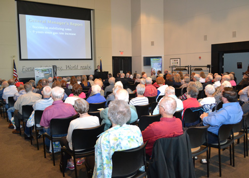 More than 120 Midwest Energy members sit in chairs as they view a PowerPoint presentation displayed on a wall to the left.  The 2015 Annual meeting was held in the Robbins Center on the Fort Hays State University Campus in Hays, Kan.