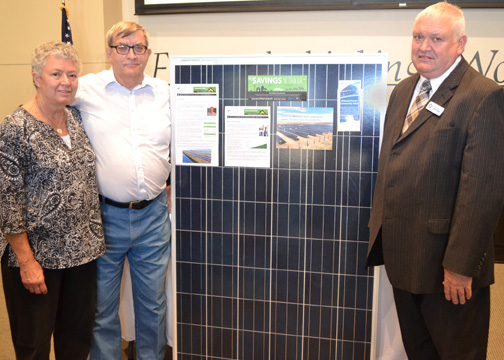 On the left, Linda and Gail Palmberg stand next to a solar panel in the community solar array they had won, as Keith Miller, Chairman of Midwest Energy Board of Directors, is on the far right side of the photo.