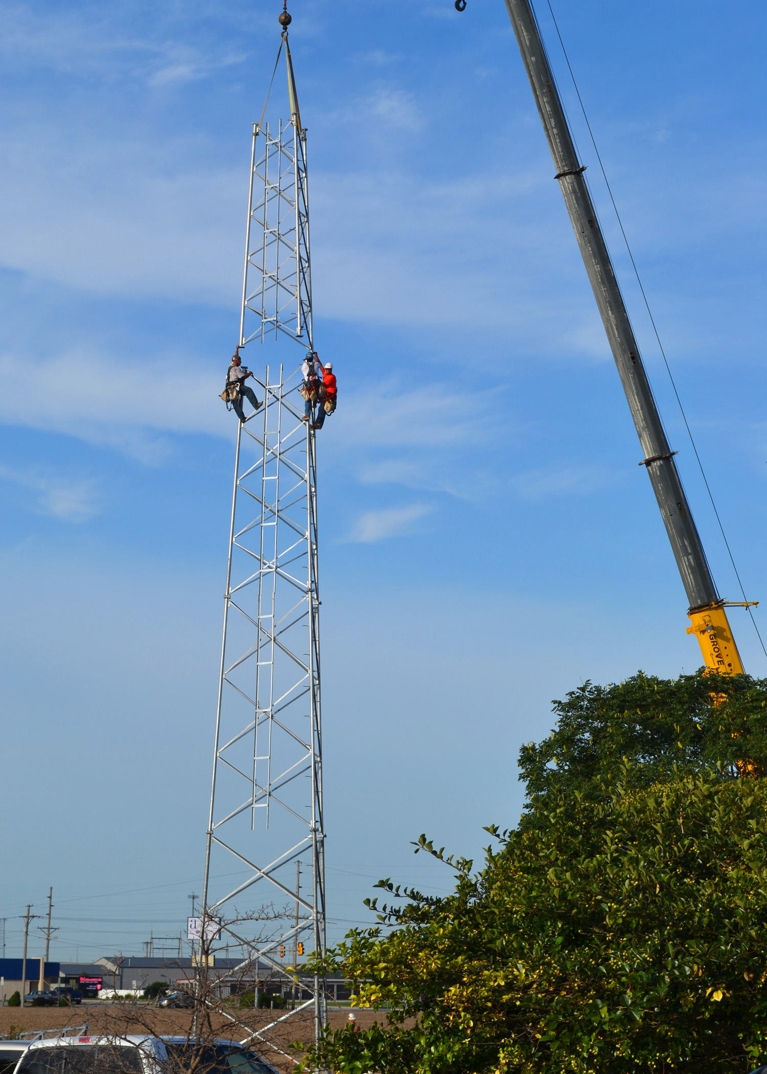 Three contractors climb the base of what will be a 150-foot tall steel communications tower at Midwest Energy's office in Hays.  The tower is one of nearly 60 system-wide to support new automated meters and other communications needs.