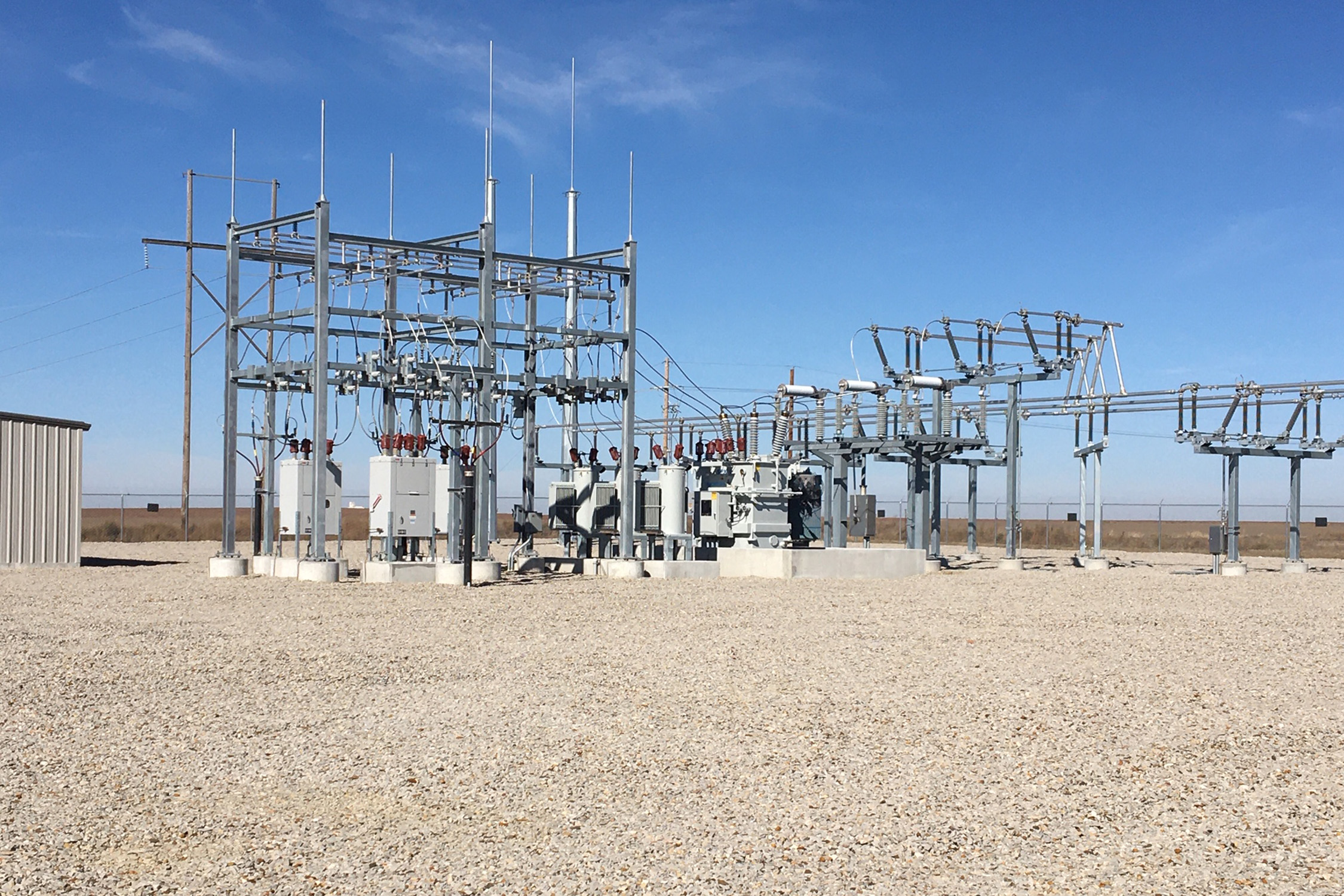 A photo of an electrical substation with steel structures and multiple transformers.