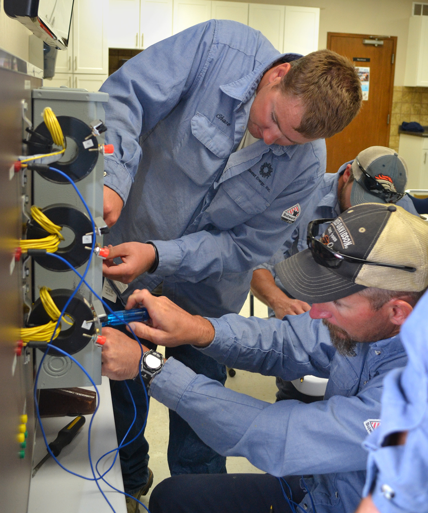 A picture of two Midwest Energy linemen in blue shirts work on a metering can simulator.