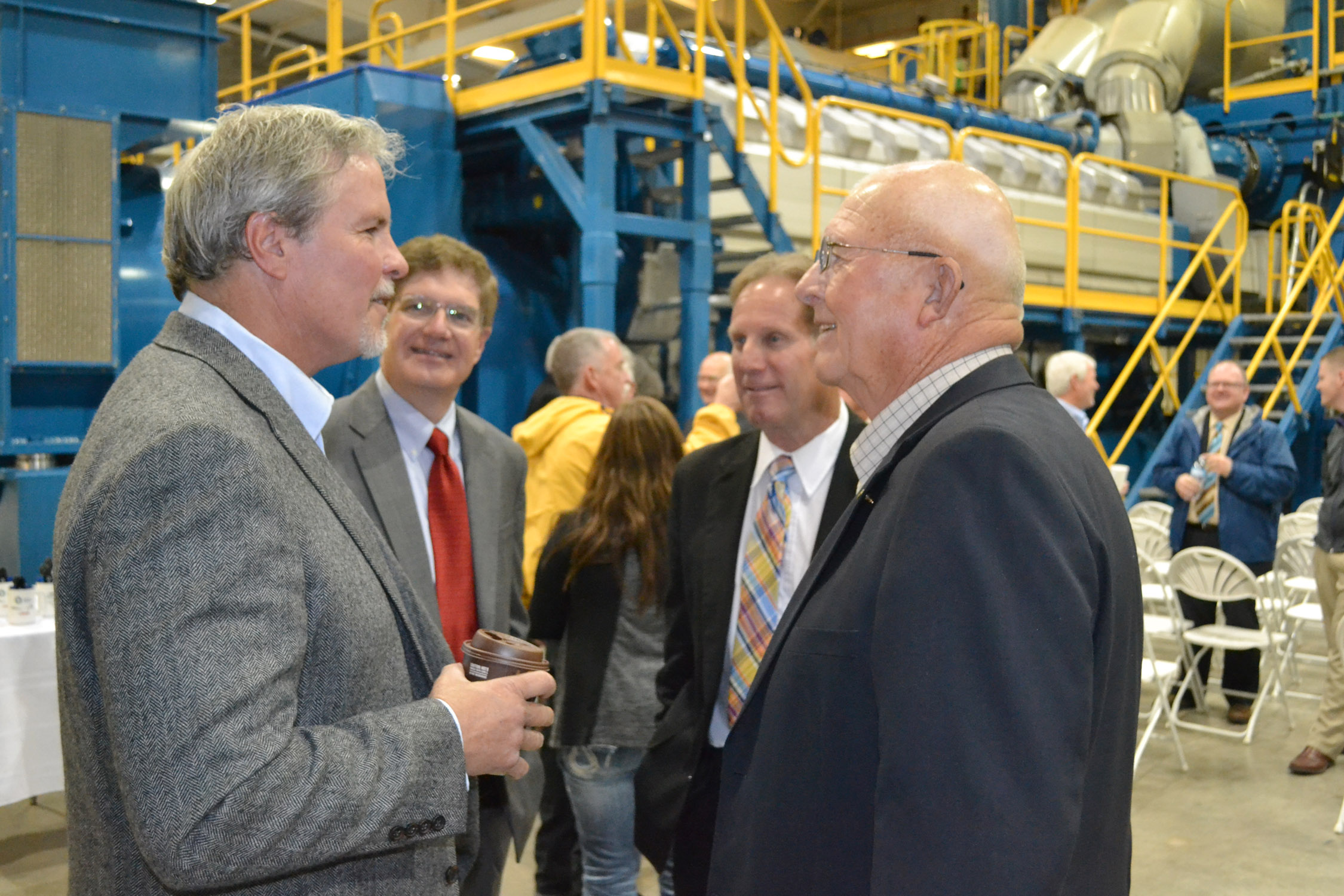 (L to R foreground) Gary Moss, member of Midwest Energy's Board of Directors, talks with Senator Ralph Ostmeyer (R-Grinnell) at the Goodman Energy Center dedication, while Bill Dowling, Midwest Energy's VP for Engineering and Energy Supply, and Rep. Rick Billinger (R-Goodland) listen.
