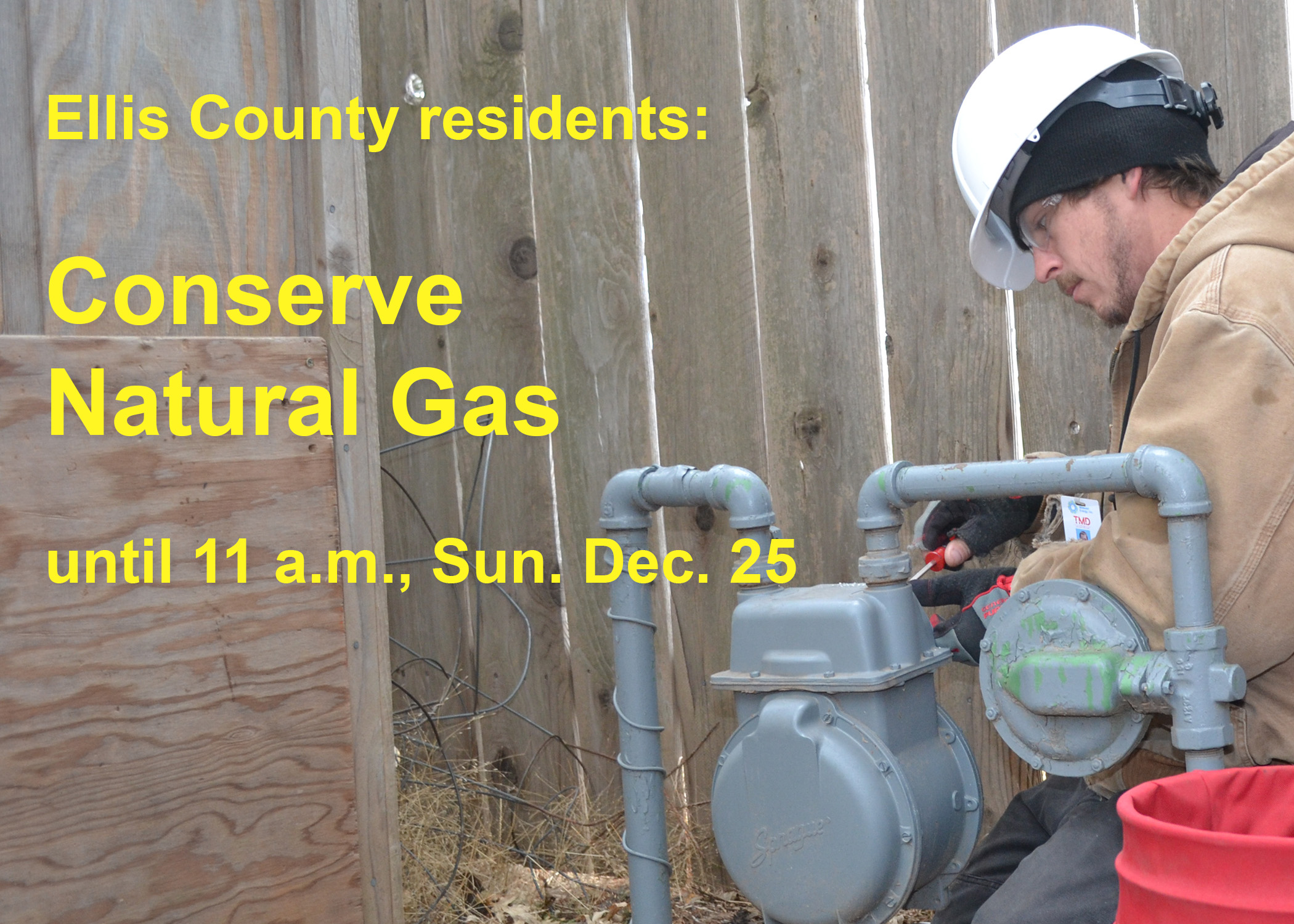 A gas technician working on a meter, with a message to conserve gas through 11 am on Sunday, Dec. 25.