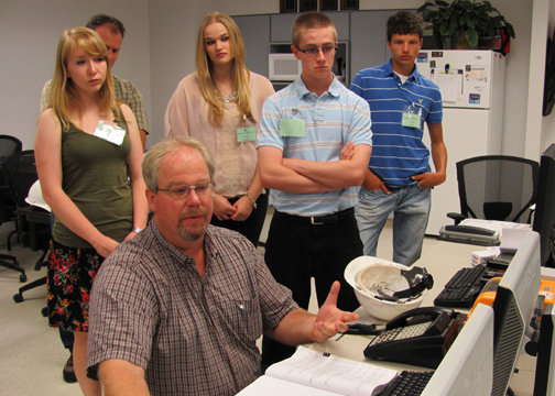 Mike Prindle, Plant Manger of Midwest Energy's Goodman Energy Center, demonstrates the plant's operating console to students selected to represent Midwest Energy during a week-long