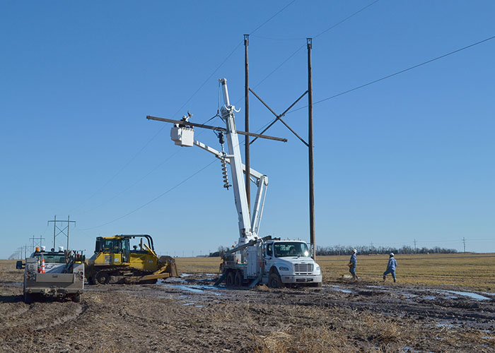 Great Bend crews fight mud nearly eight inches deep in spots, relying on a bulldozer to tow trucks in to replace a broken crossarm on a transmission pole southeast of Belpre, Kan.