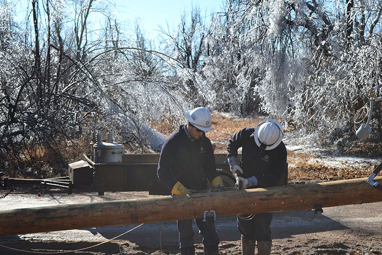 Midwest Energy linemen from Hays build a new pole to replace one that broke near Garfield, Kan.  The trees in the background show evidence of the nearly two inches of ice deposited on them by Ice Storm Jupiter.