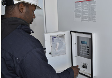 A technician from Schneider Electric turns a switch on an inverter, making the Community Solar Array