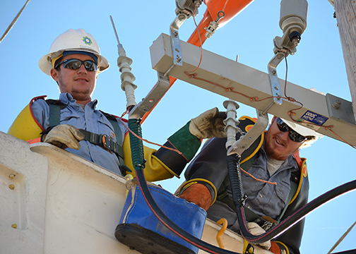 A photo of Midwest Energy linemen Weston Riffel from Colby, and Brandon Salmans of Hoxie, make final connections before energizing a section of line.