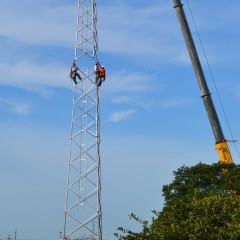 Three contractors climb the base of what will be a 150-foot tall steel communications tower at Midwest Energy's office in Hays.  The tower is one of nearly 60 system-wide to support new automated meters and other communications needs.
