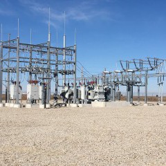 A photo of an electrical substation with steel structures and multiple transformers. 