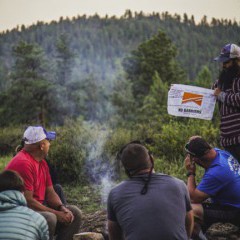 A group of veterans participating in the No Barriers Warriors program sit and talk around a campfire in the mountains near Red Feather Lakes, Colorado.  