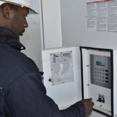 A technician from Schneider Electric turns a switch on an inverter, making the Community Solar Array 