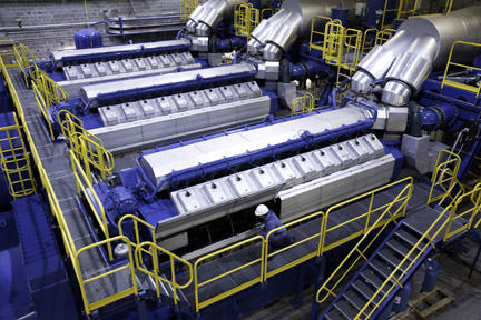 A technician is dwarfed by a Wärtsilä natural-gas powered internal combustion engine at Midwest Energy’s Goodman Energy Center in Hays, Kan. Midwest Energy is beginning a $30 million expansion of the facility in 2015, which will add three new engines and 27 megawatts of generating capacity to the facility.