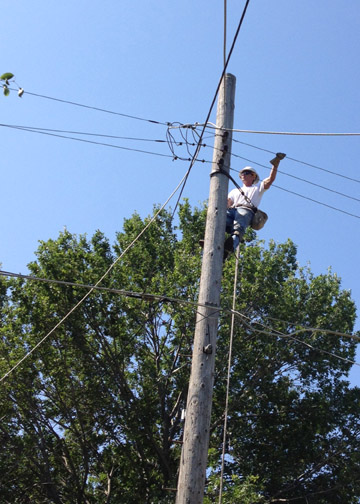 Shane Wente, Acting Line Foreman at Colby, climbs a pole to make repairs to wires in Wichita.