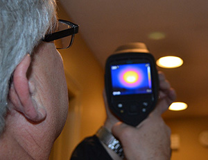 A Midwest Energy auditor uses an infrared camera to measure energy loss around ceiling lights during a whole-home energy audit.