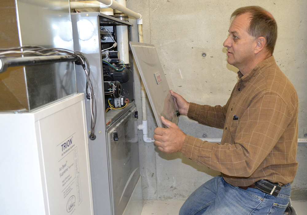 A Midwest Energy auditor inspects a newly-installed HVAC unit, for a customer participating in the Howsmart program.